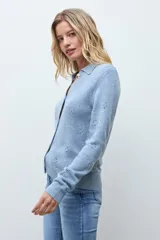 Cardigan de punto color ocre, con diseño calado de pequeños motivos florales, cuello polo y cierre frontal con botones.
