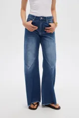 Pantalón jean gris de tiro alto, corte ancho (wide leg) con diseño de paneles tipo patchwork y terminación desmechada en el dobladillo.