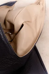 Bolso de hombro color beige, confeccionado en cuero sintético con interior plateado. Presenta un bolsillo externo con cierre.