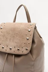 Mochila negra de símil cuero texturizado con tapa en acabado gamuzado, decorada con apliques de tachas metálicas. Tiene asa superior y correas regulables.