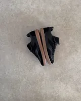 Zapatillas urbanas de cuero vacuno color negro con suela marrón.