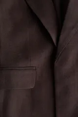 Blazer entallado de color marrón, con hombreras, solapas de muesca, mangas tres cuartos fruncidas y bolsillos delanteros con solapa. Diseño sin cierre y totalmente forrado.