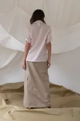 Camisa rosada con estampado de anclas y rayas sutiles, de manga corta, cuello clásico y cierre frontal de botones.
