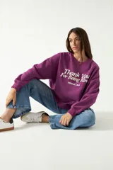 Buzo color violeta con cuello redondo, mangas largas y puños ajustados. Estampa frontal con la frase "Thank You For Being Kind" en letras blancas y el logo "Mistral Club" debajo.