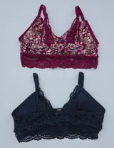 Pack de dos bralettes de encaje marca Jessica Simpson. Uno es de encaje negro y el otro es estampado floral con base borgoña y breteles fijos.