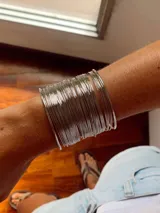 Brazalete rígido compuesto por múltiples aros finos plateados que forman una pulsera ancha.