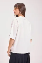Remera de corte oversize y mangas cortas, color blanco, con cuello redondo y detalle de etiqueta pequeña en la manga.