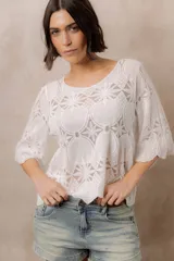 Blusa de punto liviano color blanco con diseño geométrico y floral, escote redondo y mangas tres cuartos amplias con transparencias.