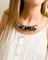 Gargantilla dorada con piedras cuadradas nacaradas en tonos grises y negros.