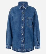 Camisa de corte oversized confeccionada en denim de algodón con lavado gris desgastado. Presenta cuello clásico, cierre frontal con botones metálicos, manga larga con puños abotonados y un bolsillo aplicado en el pecho. El diseño incluye un bajo redondeado.