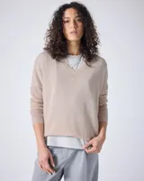 Sweater de punto fino color gris claro, con cuello en V y mangas largas. El tejido parece ser ligeramente transparente o muy liviano.