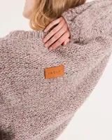 Buzo tejido a mano con lana, color rosa con motas de colores. Diseño oversized, largo entre la cintura y la cadera, con detalle de trenzas en las mangas.