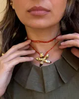 Collar tipo gargantilla con dije de flor metálica de acabado brillante, suspendido de un cordón doble de seda natural teñido a mano en color rojo.