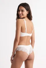 Colaless blanca de tejido acanalado con detalles de encaje floral en los laterales y placa metálica decorativa.