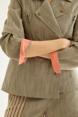 Chaqueta a rayas en tonos beige y marrón, cruzada con solapas, bolsillos con cierre y detalles internos en tono salmón en los puños.