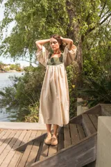 Túnica midi de lino color beige con pechera en contraste de color verde oliva con diseño estampado. Presenta mangas abullonadas con puños elásticos y corte holgado con frunces.