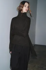 Jersey de lana con cuello subido, manga larga y bajo asimétrico con detalle de nudo lateral. Presenta acabados en rib en cuello, puños y ruedo.