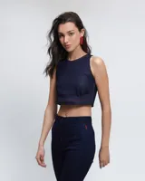Top corto tipo halter de jean azul oscuro, con cuello a la base, pinzas delanteras para mayor estructura y pespuntes en color rojo. Cuenta con cierre lateral y abertura con botón en la espalda.