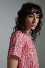 Blusa estampada fucsia y beige con cuello redondo y mangas cortas con volados.