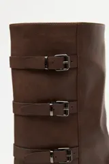 Bota de caña alta estilo biker, color negro, con plataforma robusta y suela dentada. Presenta múltiples tiras laterales con hebillas metálicas ajustables.