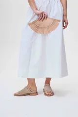 Sandalias bajas de cuero color beige con detalle de tachas metálicas en la tira delantera.
