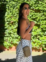 Bandolera compacta color rosado, con correa regulable y desmontable. Tiene apertura superior, bolsillo frontal con cierre y detalle de borla, y bolsillo trasero sin cierre. El interior está forrado en tela y cuenta con un bolsillo adicional.