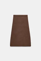 Falda midi de punto color crudo, con tiro medio, cintura elástica y diseño evasé.