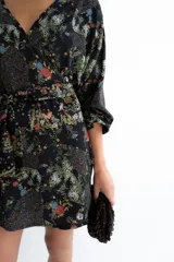 Kimono negro con estampa floral multicolor, escote en V cruzado, mangas largas con elástico en los puños y lazo ancho ajustable en la cintura.