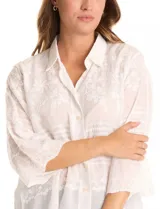 Camisa de algodón broderie color blanco, marca Liv Los Ángeles. Cuello con solapa, abertura central con botones y mangas ¾ amplias.