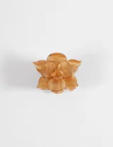 Broche para el cabello con forma de flor, hecho de acrílico color ámbar con vetas y brillo sutil.