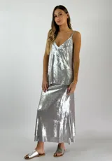 Conjunto plateado brillante de top con breteles finos y pollera larga con efecto mojado.