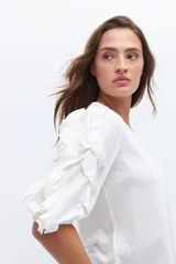 Remera color beige con mangas cortas y volados con borde naranja.