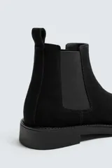 Bota estilo Chelsea de hombre, confeccionada en piel con acabado de serraje en color marrón. Presenta elásticos laterales oscuros para facilitar el calce, horma redonda y suela a tono con un ligero tacón.