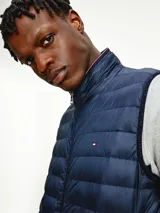 Chaleco acolchado azul marino con cierre de cremallera, cuello alto y logo de Tommy Hilfiger bordado en el pecho.