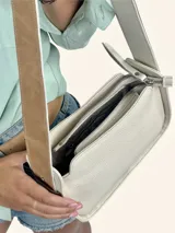 Bolso tipo baguette color crudo con doble correa al hombro de cuero color camel.