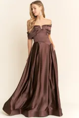 Vestido largo de fiesta confeccionado en satén color marrón chocolate. Presenta un diseño strapless con escote tipo solapa que cae sobre los hombros, cuerpo entallado y falda amplia con vuelo y bolsillos laterales.