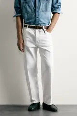 Jeans relaxed fit color blanco, de corte recto y tiro medio con tejido de algodón rígido. Cuenta con cinco bolsillos, efecto ligeramente lavado, perneras con raya de planchado y cierre frontal con cremallera y botón.