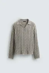 Polo de algodón tejido con estructura de trenzas, cuello solapa con abertura frontal en V y manga larga. Presenta acabados en rib con efecto roto en puños, cuello y ruedo.