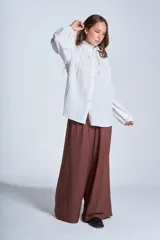 Camisa de color azul con cuello alto decorado con volados y lazo de ajuste. Presenta tablas decorativas en los hombros, cierre frontal con botones de nácar y mangas largas con puños elásticos que generan un efecto abullonado.