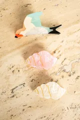 Broche con forma de caracola color blanco nacarado con detalles dorados.