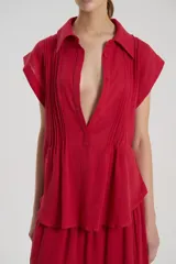 Camisa sin mangas de bambula de algodón color rojo, con cuello camisero, detalle de alforzas en el delantero y cartera de botones frontal.