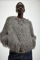 Chaqueta de cuello redondo y manga larga, confeccionada con textura de flecos en toda la prenda. Presenta cierre frontal con ganchos ocultos y un diseño corto.