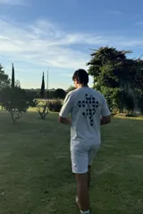 Remera de manga corta color gris claro, con cuello redondo y un estampado abstracto en negro en la espalda.