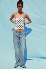 Top blanco con estampado de lunares negros, escote recto, hombros descubiertos y detalle de frunces.