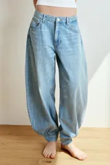 Jeans de tiro medio y diseño balloon, color azul denim con efecto lavado, cinco bolsillos, cierre frontal con cremallera y botón metálico, y bajos acabados en puño.