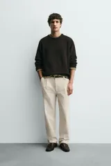 Pantalón relaxed fit color beige confeccionado en tejido de algodón con tacto suave, cintura con pliegues delanteros y cierre frontal con cremallera y botón.