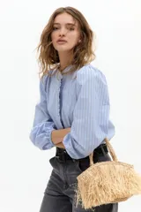 Camisa de algodón con estampado de rayas verticales en tonos azul y blanco. Presenta cuello mao, cierre frontal oculto con detalle de volado lateral y mangas abullonadas con puños elásticos.
