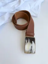 Cinto de cuero color tostado con hebilla rectangular de guampa con marco metálico. El broche suizo permite intercambiar la hebilla.