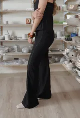 Pantalón negro de corte acampanado, con costuras visibles y laterales de encaje negro con textura.