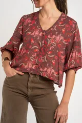 Blusa de viscosa color marrón con estampado floral en tonos rosados y rojos, de corte oversize, cuello en V con detalles de encaje y mangas largas abullonadas con inserciones de encaje.